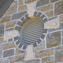 Round window with four stone keystones and wings.