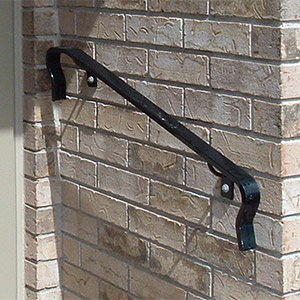 Black handrail on a brown brick wall.