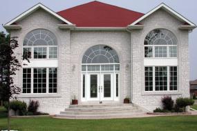 Shouldice Designer Stone - Grey house with front door and windows with Roman surrounds